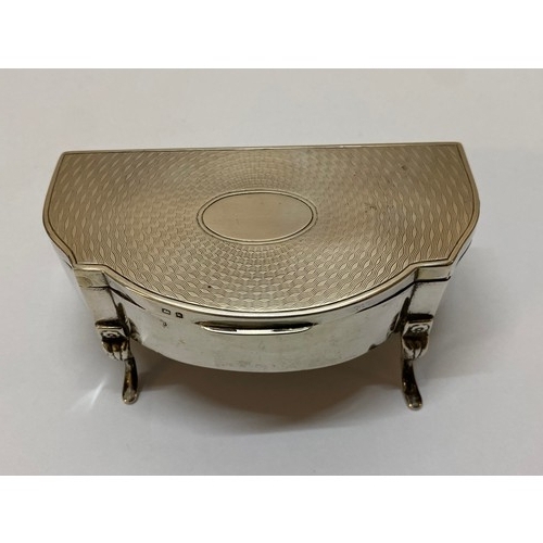 276 - A silver trinket box with vacant oval cartouche and engine turned decoration to the lid, raised on f... 