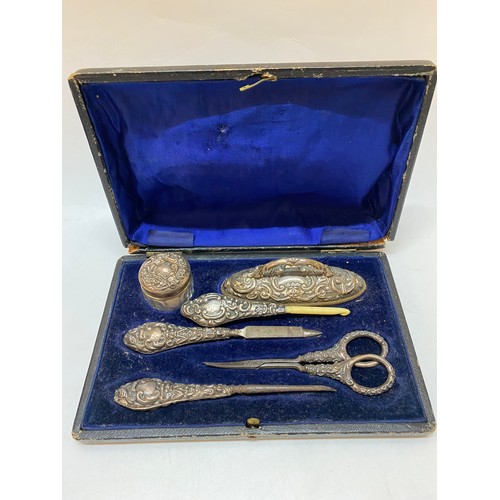 260 - A lady's five piece manicure set mounted in repousse decorated silver and a similar handle, in fitte... 