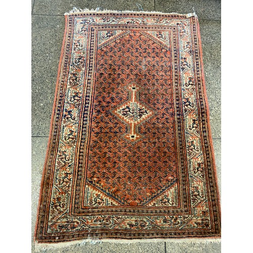 14 - An Eastern rug, red field with blue geometric decoration and stylised medallion to the centre, cream... 