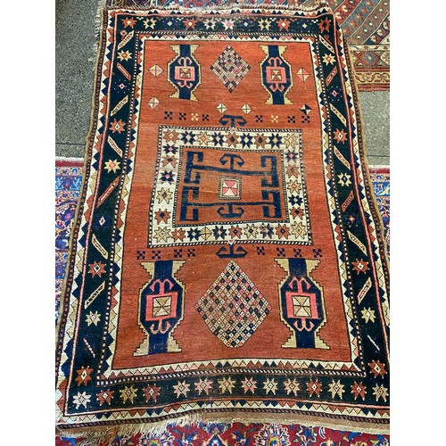 16 - An Eastern rug, rust field with stylised decoration to the centre in cream, red and blue within styl... 