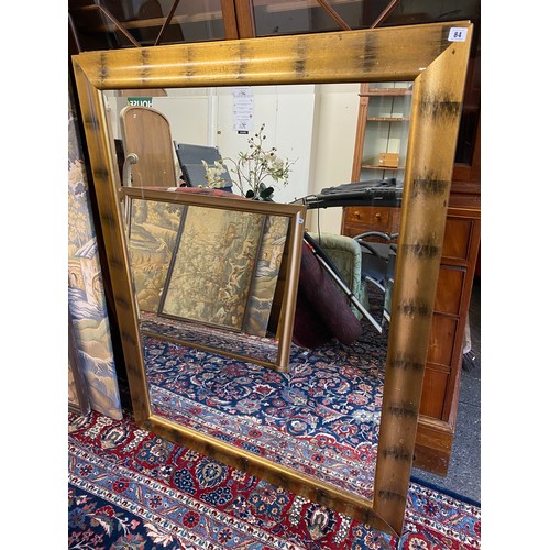 84 - A modern rectangular bevelled wall mirror in a gold sprayed frame - 56in. x 43in.