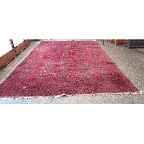 1 - A large Eastern Bokhara style carpet, red field with twenty one medallions to the centre, fringed - ... 