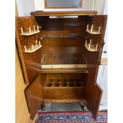 47 - A reproduction walnut veneered cocktail cabinet, the upper part fitted two doors with decorative gil... 