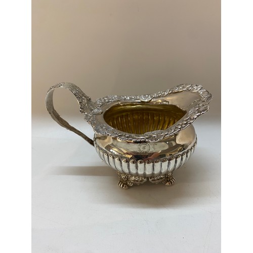 194 - A heavy silver milk jug with repousse flower decorated border and handle, gadroon decoration, on fou... 