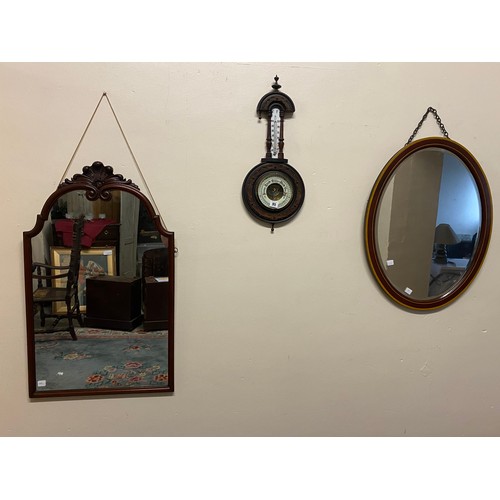 95 - A shaped wall mirror in a mahogany frame with leaf pediment - 32in. x 20in., an oval wall mirror in ... 