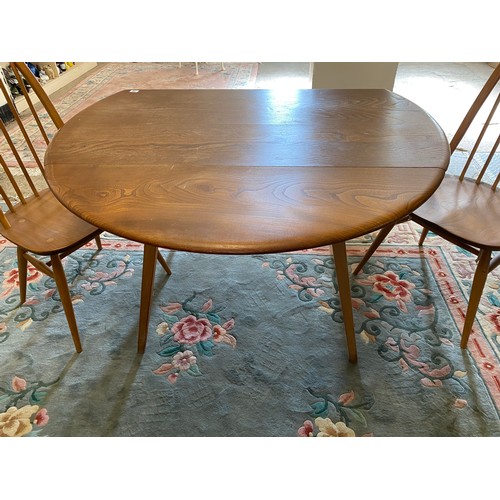 70 - An Ercol dining table with two drop flaps on straight legs - 44 1/2in. wide and two Ercol two high s... 