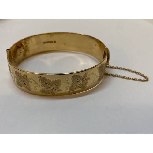 178 - A heavy 9ct. gold hinged bangle with engraved decoration to the top