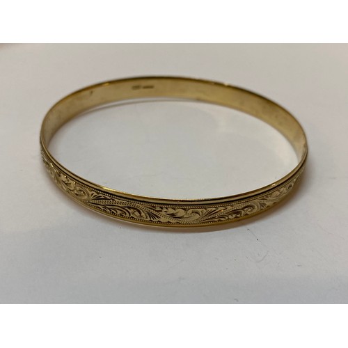 181 - A 9ct. gold bangle with chased leaf scroll decoration