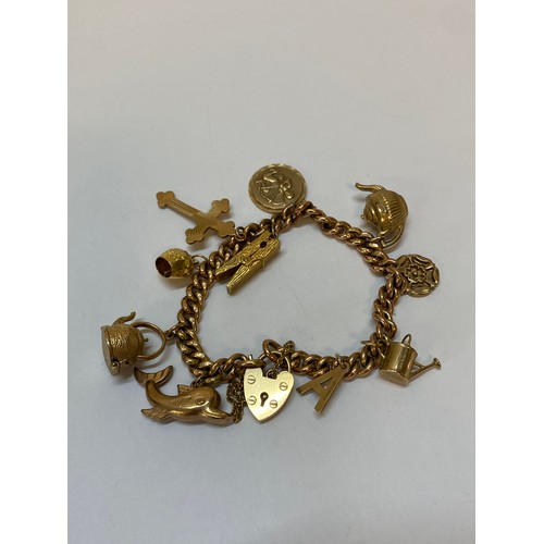 183 - A 9ct. rose gold bracelet with heart shaped padlock hung with 9ct. gold charms including a teapot, w... 