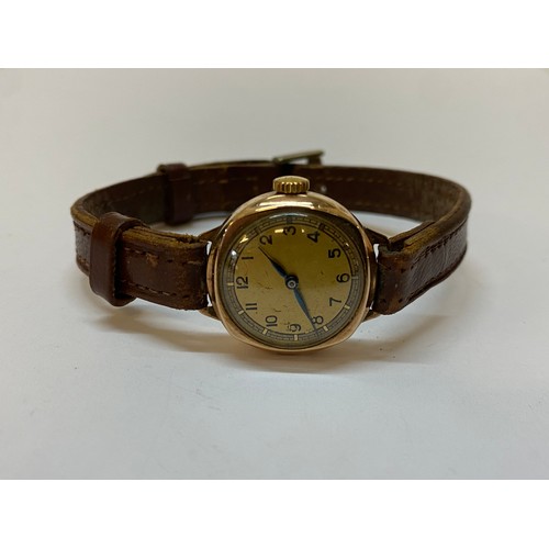 196 - A lady's wristwatch in a gold case, on a brown leather strap
