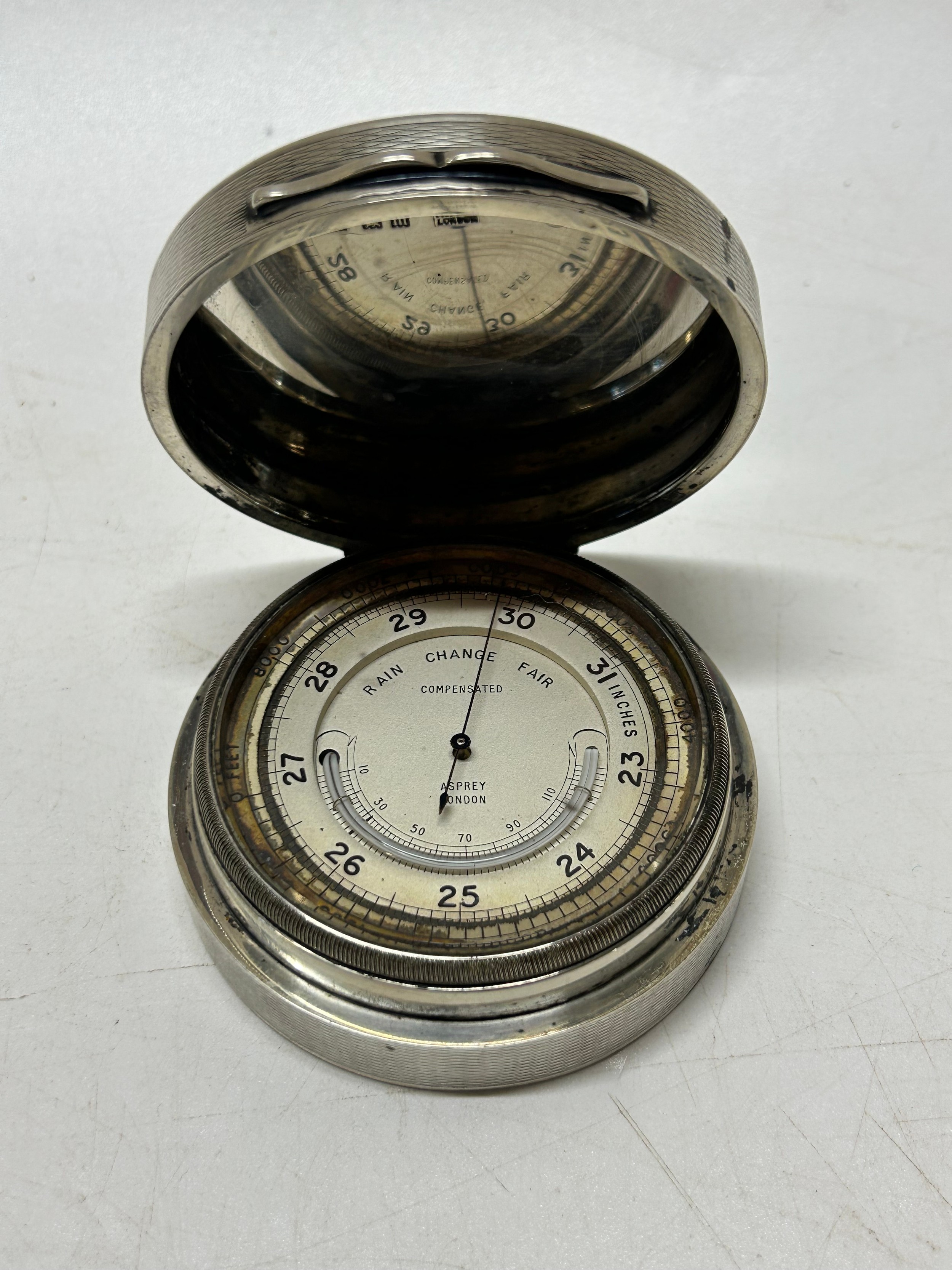 A compensated desk barometer and thermometer in an engine turned silver ...