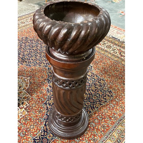 100 - A brown glazed pottery jardiniere of wrythen form, on column - 33in. high