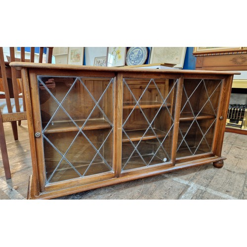 374 - Mahogany glazed bookcase with three leaded sliding doors, one glass panel cracked