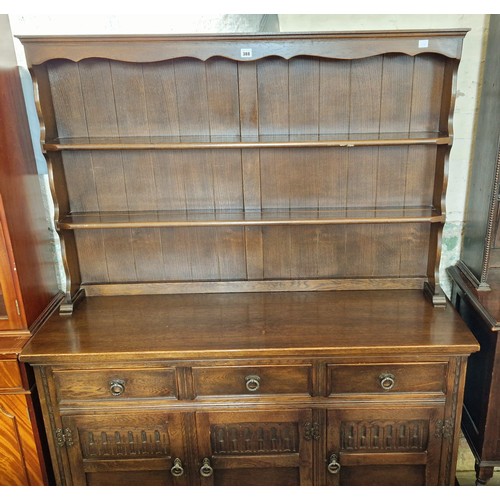 388 - 20th Century oak dresser with plate rack over a base of three drawers and cupboards