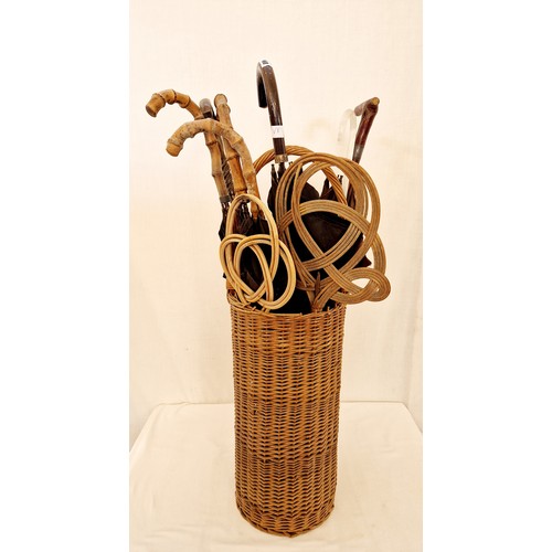 160 - Cylindrical wicker stick stand and various bamboo handled umbrellas, cane carpet beaters etc