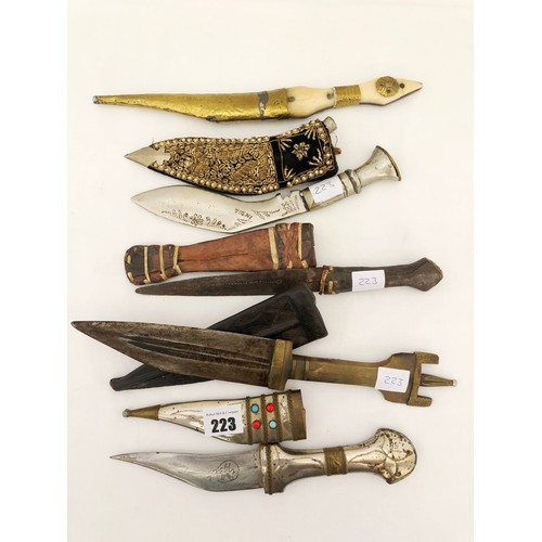 223 - A group of five eastern and Indian daggers, including ornamental jewelled and embroidered sheaths