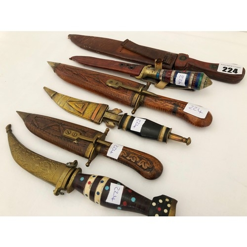 224 - A group of six eastern and Indian daggers with carved wooden brass & leather sheaths