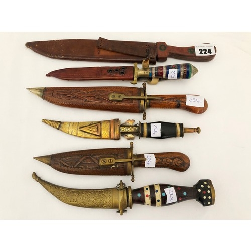 224 - A group of six eastern and Indian daggers with carved wooden brass & leather sheaths