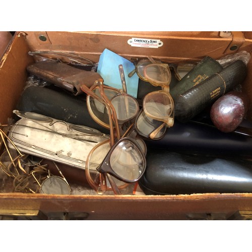 104 - Two small leather box cases, one containing a quantity of cased and loose wire rimmed spectacles etc