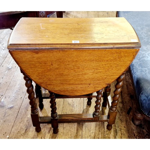 304 - A mid-century oak oval drop leaf table on barley twist legs