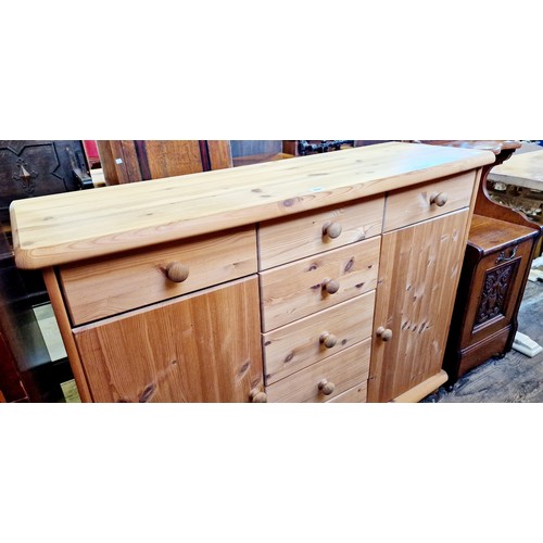 330 - A modern pine side cabinet with 3 frieze drawers over a central bank of 4 drawers flanked by 2 cupbo... 