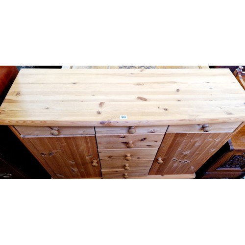 330 - A modern pine side cabinet with 3 frieze drawers over a central bank of 4 drawers flanked by 2 cupbo... 