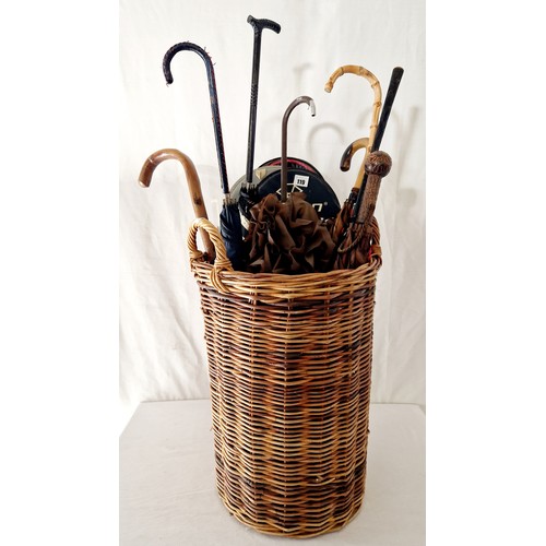 119 - Cylindrical wicker basket with various parasols, badminton rackets etc