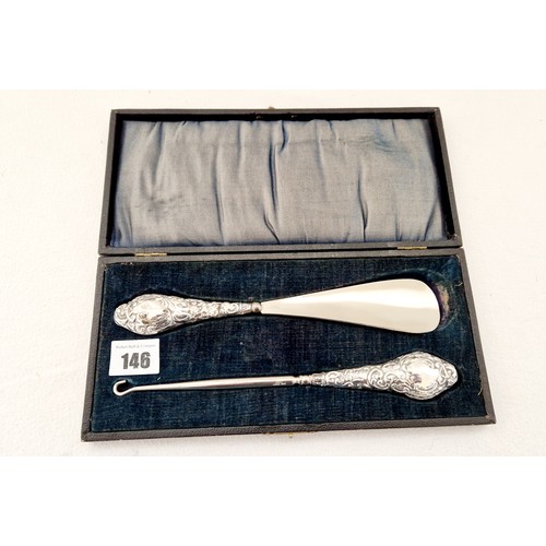 146 - A cased set of shoe horn and button hooks, with profusely embossed silver handles