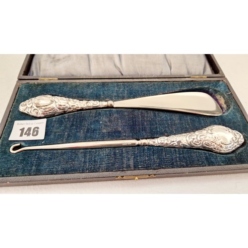 146 - A cased set of shoe horn and button hooks, with profusely embossed silver handles