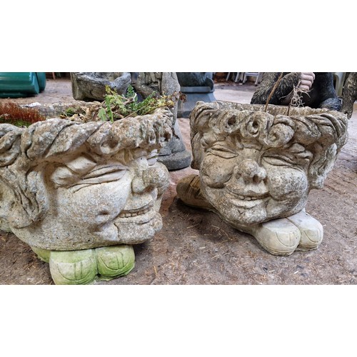 61 - Two simulated stone garden figures and a pair of planters on feet