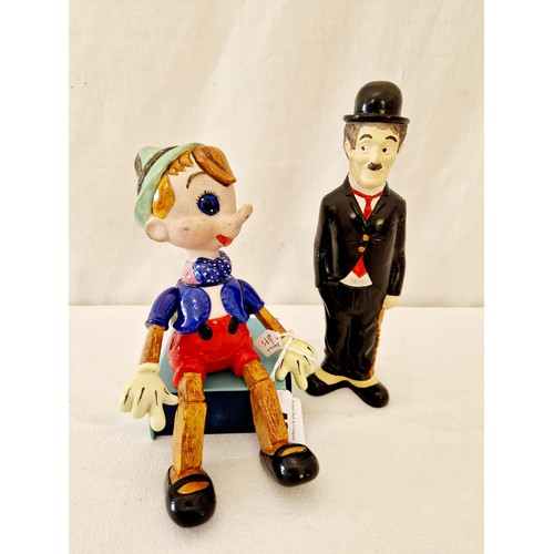 48 - Two figurines comprising Pinocchio with metamorphic arms and a plaster Charlie Chaplin