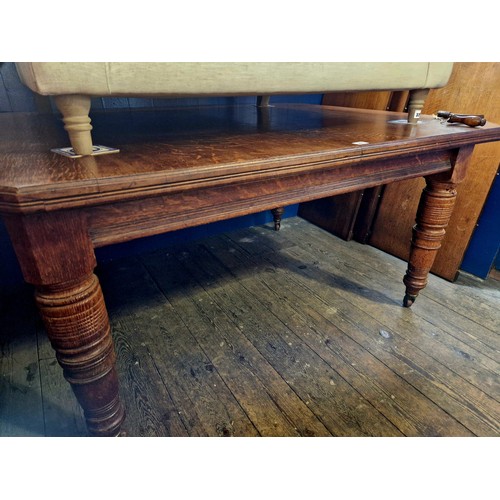 327 - Edwardian oak rectangular wind-out dining table with 3 spare leaves on turned legs to castors