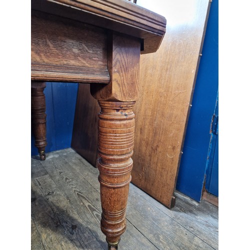 327 - Edwardian oak rectangular wind-out dining table with 3 spare leaves on turned legs to castors