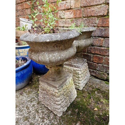 443 - Pair of simulated stone pedestal garden urns on concrete plinths