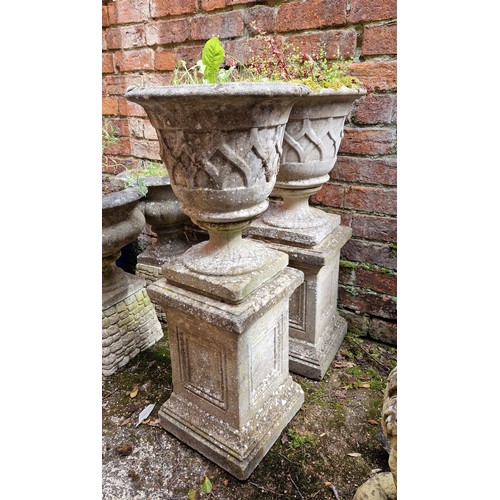 444 - Pair of simulated stone pedestal urns on classical pattern plinths