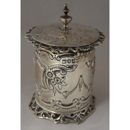 4 - A silver cylindrical container, London 1896, maker George Maudsley Jackson, with hinged lid and embo... 