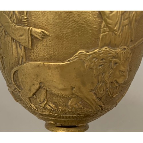 33 - A gilt brass Romanesque urn, 19th century, decorated with seven figures and a lion in high relief, s... 
