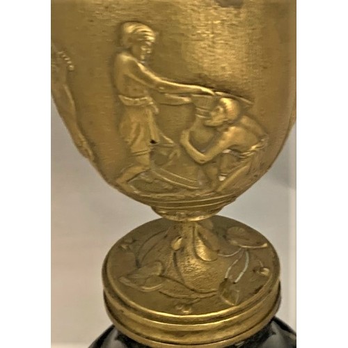 33 - A gilt brass Romanesque urn, 19th century, decorated with seven figures and a lion in high relief, s... 