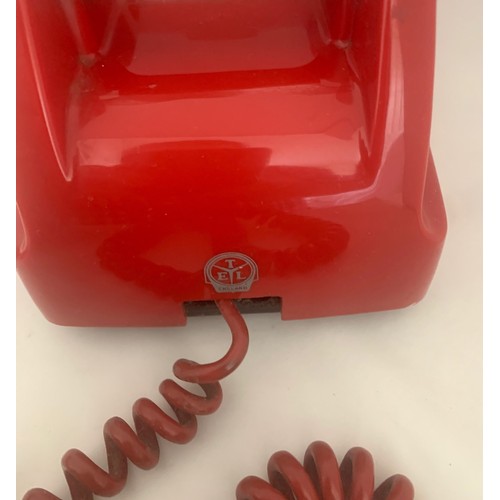 112 - A vintage red rotary dial wall mounted telephone.