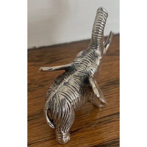 124 - A cast white metal standing and trumpeting elephant, 4 cm wide.