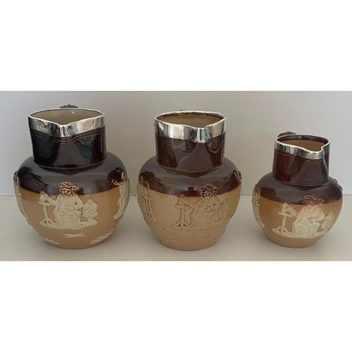 5 - A matched set of three Doulton Lambeth salt glazed and two tone jugs with silver collars, each with ... 