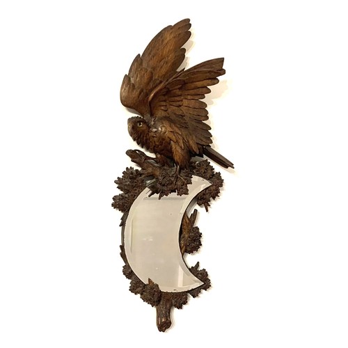 136 - Black Forest carved walnut wall mirror, with crescent-shaped bevelled glass. the mirror supported by... 