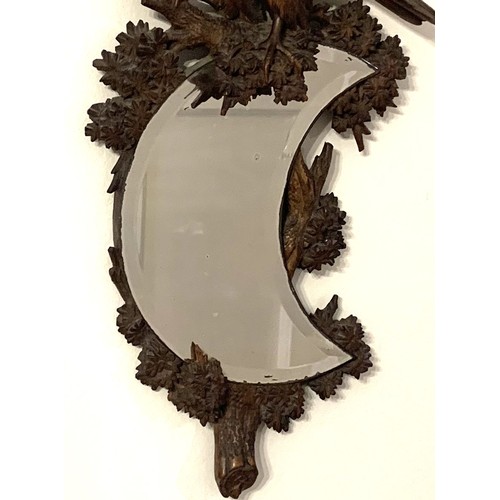 136 - Black Forest carved walnut wall mirror, with crescent-shaped bevelled glass. the mirror supported by... 