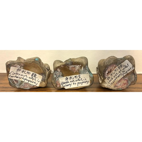 10 - A set of three cast metal Buddha figures, on a rock form resin stand, with Chinese inscriptions to t... 