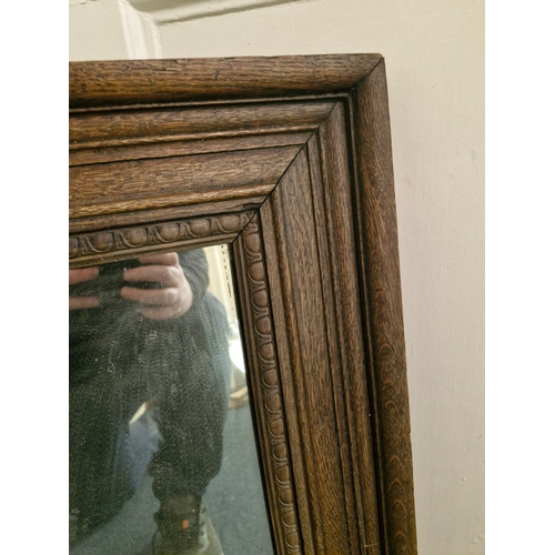 54 - A nice sized and heavy mirror in a solid oak frame.. marked Bass and Co.