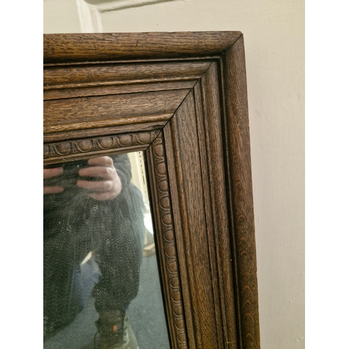 54 - A nice sized and heavy mirror in a solid oak frame.. marked Bass and Co.