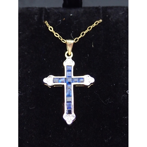 101 - A gold diamond and sapphire cross pendant on chain