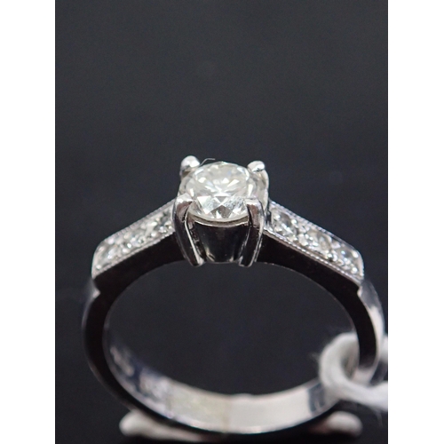 45 - A diamond solitaire ring, set with diamond shoulders. Showing as finger size J and a half