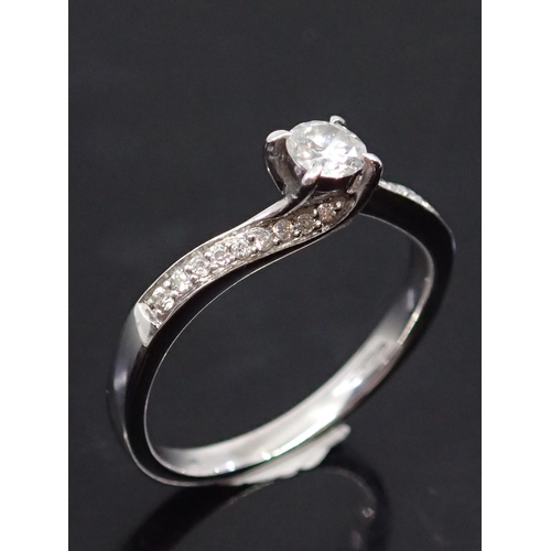 15 - An 18ct gold diamond solitaire ring set with diamond shoulders, finger size N