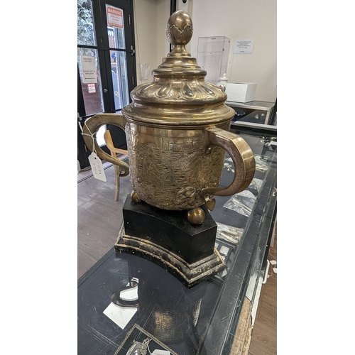 269 - A silver three handle cup approx 1138 grams on wooden plinth, the cup is hallmarked Chester 1902 by ... 